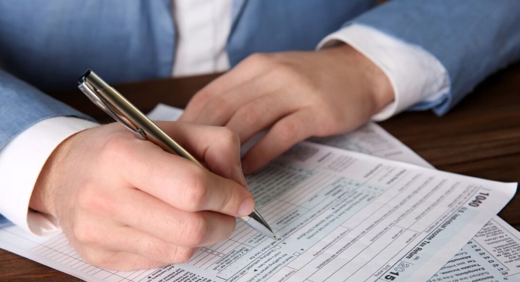 Mulher em frente a um computador com gráficos contábeis e notas fiscais, representando a organização das obrigações acessórias de uma empresa.