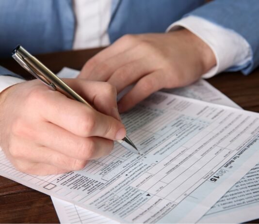 O Que São Obrigações Acessórias e a Sua Importância Mulher em frente a um computador com gráficos contábeis e notas fiscais, representando a organização das obrigações acessórias de uma empresa.