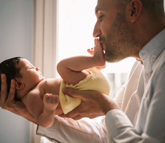 A Evolução da Licença Paternidade no Brasil: Um Comparativo Global e Seus Novos Benefícios para Pais Pai segurando bebê recém-nascido, simbolizando a Licença Paternidade e o vínculo familiar.