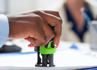 Conta Notarial já está disponível em todo o Brasil: entenda como ela funciona e por que pode facilitar sua vida Tabelião em cartório digital mostrando no tablet o uso da Conta Notarial com casal ao fundo assinando escritura.