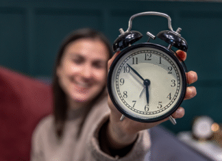 Banco de Horas ou Hora Extra: Decifrando as Diferenças para Gestão Inteligente Funcionário em frente a um relógio de ponto, decidindo entre banco de horas ou hora extra, com a CLT ao lado.